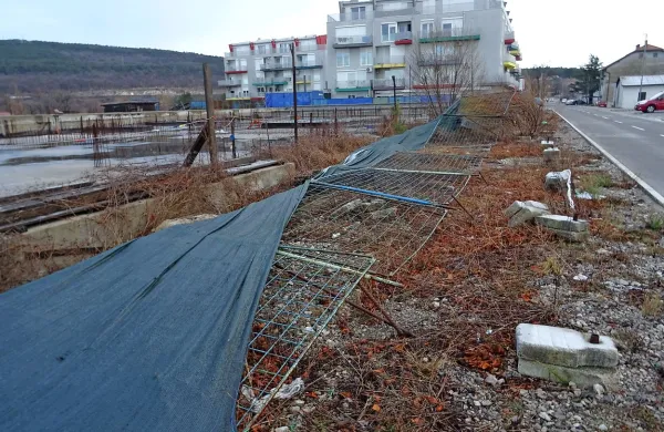 Mrežna ograja in na njej napeto platno je na tleh in razkriva nič kaj mikavno podobo 
nedokončanega gradbišča.