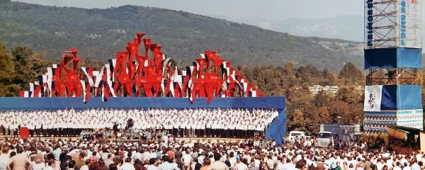 Proslava v Komnu leta 1978: oder, odet v modro barvo, za njim 
Triglav iz zastav, na desni stolp z napisom 1943-78 in sliko Tita.