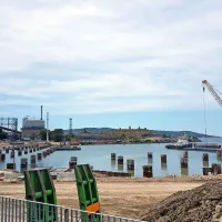 Lani so v Trstu še zabijali jeklene pilote v morsko dno, danes pa na 
tej pilotih že stoji 12 hektarjev velika logistična ploščad s 480 metri 
obale. Gradi in upravlja jo podjetje Piattaforma Logistica Trieste 
PLT, ki je v lasti štirih družbenikov (špediter Parisi ima 46 
odstotkov, gradbena družba Icop 44 odstotkov, Autoporto Bologna 
šest odstotkov in okoljska družba Cosmo Ambiente štiri odstotke), 
vodi pa ga Drago Matić. V  Kopru pa za podaljšanje prvega pomola 
za 100 metrov niso zabili še niti testnih pilotov, tako da se bo 
začetek strateške investicije, ki so jo predvideli za letošnji maj, še 
dodatno zamaknil.      