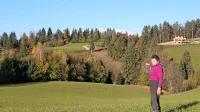 Gospa Dora Mlinar, katere družino hočejo nasilno razlastiti, kaže na rob gozda, kamor bi želeli premestiti sporno pot.