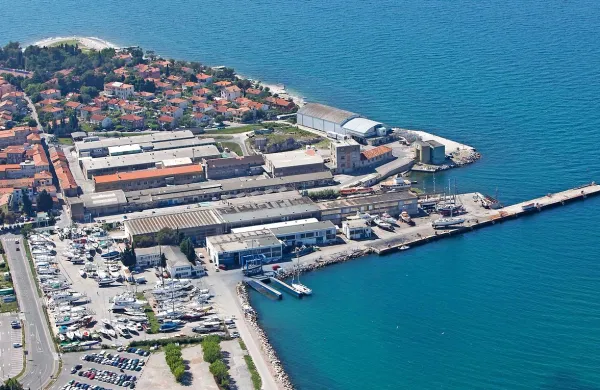 Za javnim parkiriščem je zemljišče ladjedelnice in   za njim nekdanje Delamarisovo dvorišče (vmesne parcele so  v lasti nekdanjih 
Delamarisovih lastnikov). Če bi kdo kupil oboje, bi dobil osem 
hektarjev  veliko območje.    