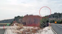 Pogled na merilni stolp (v rdečem krogu) s ceste pri Čebulovici.   100-metrski stolp na vrhu hriba Na Gavgah pri Zajčici je bil, dokler  
agencija za letalski promet ni povišala meje letenja,   za pilote potencialna nevarnost. 