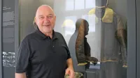  Lawrence Chalmer v  pivškem vojaškem muzeju pred vitrino z 
uniformo ameriškega letalca iz druge svetovne vojne.  