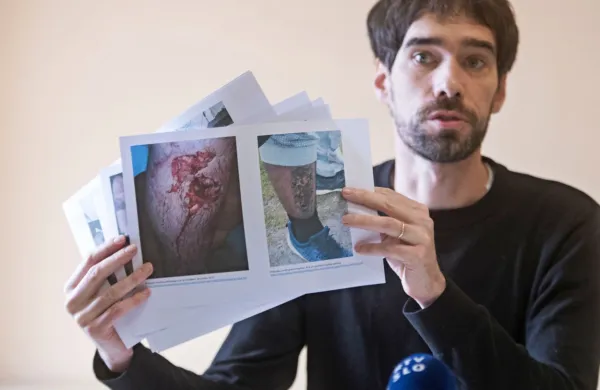 Miha Blažič iz Delovne skupine za azil kaže fotografije ranjenih  
migrantov, ki naj bi jih pretepli hrvaški policisti.