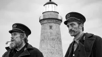 Dva moška, svetilničar in njegov vajenec - Willem Dafoe (levo) in 
Robert Pattinson - morata štiri tedne preživeti na odročnem 
severnoatlantskem otoku in kljubovati (nad)naravnim silam.