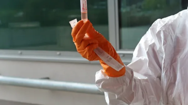 Zdravstveni delavec v roki drži test za koronavirus.

