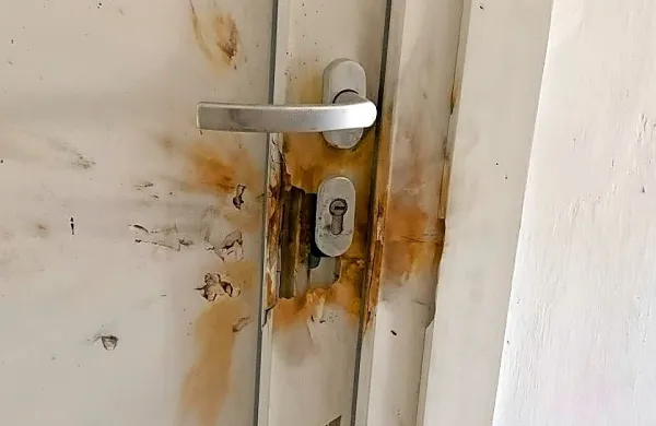Posledice, ki jih je petarda pustila na sosedovih vratih.