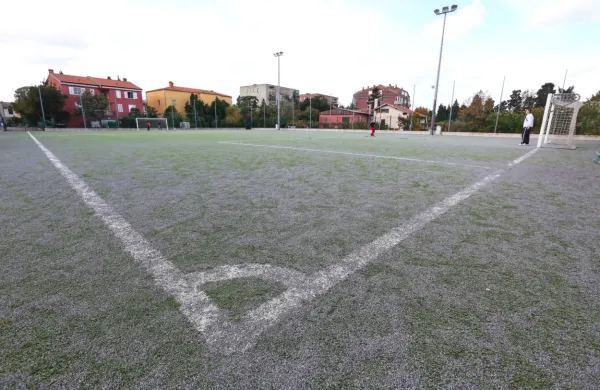 Eno od dveh pomožnih igrišč ob stadionu. Že leta 2013  je bilo na 
njem videti več polnila kot  umetne  trave, kar je botrovalo  
marsikateri poškodbi.

