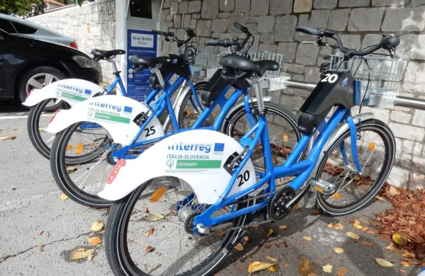  Na Krasu in v Brkinih si je možno brezplačno izposoditi električna 
kolesa (na fotografiji je postaja pri osnovni šoli v Sežani), vendar je 
v primeru okvar vzdrževalec dokaj slabo odziven.