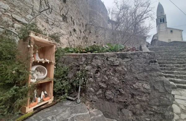 Jaslice v lični leseni vitrini, obdani z brinovimi vejami.