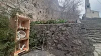 Jaslice v lični leseni vitrini, obdani z brinovimi vejami.