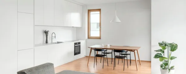 Jedilna miza z vitkimi nogami sledi odtenku hrastovega parketa, 
kontrast pa ustvarjajo črni jedilni stoli.