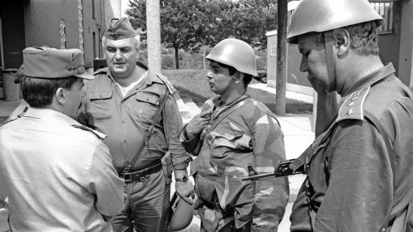 Slavko Gerzelj (levo) na fotografiji Davorina Križmančiča med pogajanji z oficirji JLA 
na mejnem prehodu Pesek. Kasneje je z nasmehom razvil slovensko zastavo.