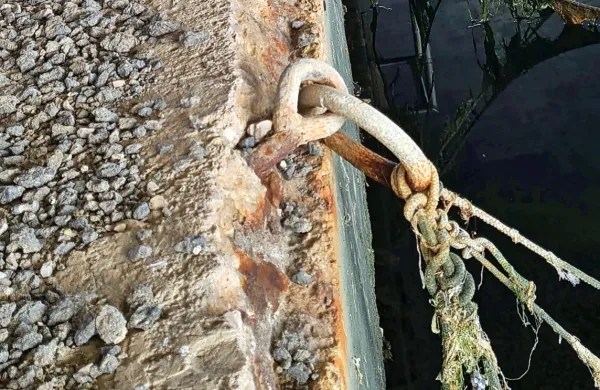 Zarjavela privezna rinka  se komaj še drži poškodovanega zidu.