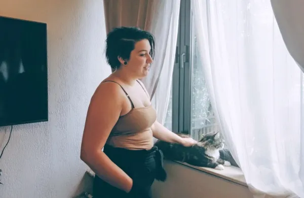 Sarah Durnik z mačkom Ashem pri oknu, skozi katerega je konec maja 2019 v njeno stanovanje vlomil Izidor H.

