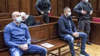 Bojan Stanojević (levo) in  Klemen  Kadivec  (desno, ob njem  
pravosodna policista) sta v priporu  od  novembra 2019,  ko so  ju 
policisti prijeli v Ankaranu.