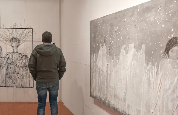 Detajl s postavitve v Pilonovi galeriji Ajdovščina, kjer je bila razstava na ogled do konca leta, prikazuje 
avtoportret Tee Curk Sorta iz žic (levo) in sliko velikega formata  Anje Kranjc iz cikla Utelešanje divjine.