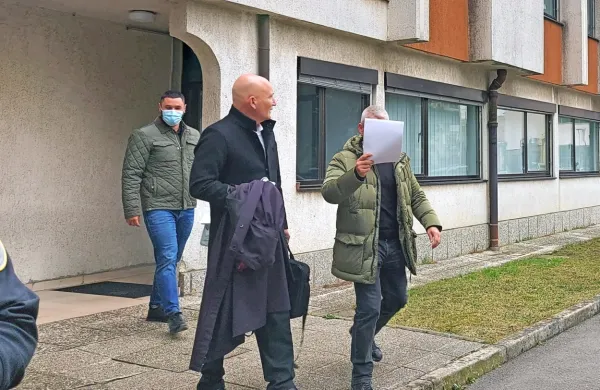 Marko  Hot  si  je  pred sodiščem  z listom  papirja  zakril  obraz,  z njim  
odvetnik Boštjan  Penko  in njegov  klient   Milutin  Stefanović.