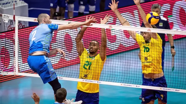 Alen Pajenk pošilja žogo čez mrežo, pod katero je  s številko 21   Alan Souza, ki je izstopal v brazilski reprezentanci. 