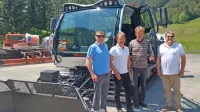 Branko Vidmar, Valter Mlekuž, Rudi Černuta in zastopnik proizvajalcev žičničarske opreme Alan Furlani (z leve) pred novim 
teptalcem, v ozadju je odsluženi 50 let star stroj.