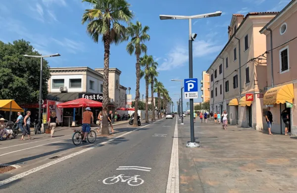 Koprska Pristaniška cesta, na kateri je kolo z dvema strešicama  - 
zdi se, da se večina kolesarjev pri vožnji vendarle raje umakne s 
cestišča na promenado. 