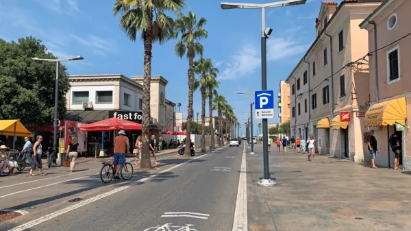 Koprska Pristaniška cesta, na kateri je kolo z dvema strešicama  - 
zdi se, da se večina kolesarjev pri vožnji vendarle raje umakne s 
cestišča na promenado. 