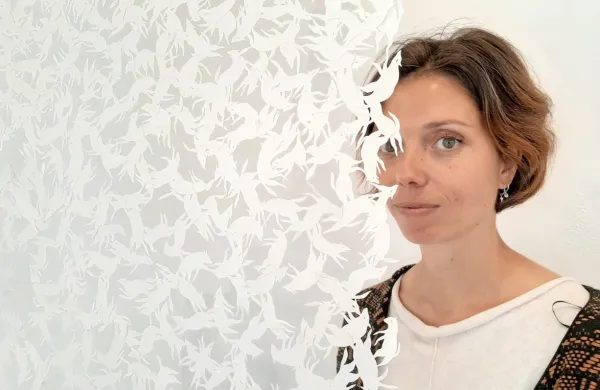 Lara Jeranko Marconi pred  zaveso iz ročno izrezanih zverinic, ki iz kaosa ustvarjajo red in obratno.  