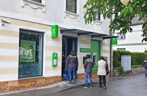 Kriminalisti so na vhodnih vratih iskali sledi za roparjema. 