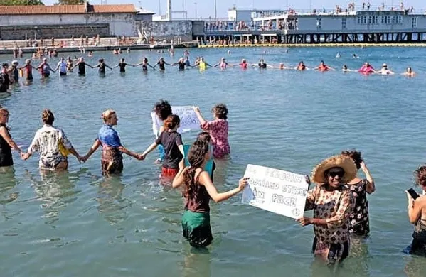 Danes se je na tržaškem kopališču Pedočin več kot 50 kopalk ob 
10.30 solidarnostno odpravilo v vodo v oblekah.