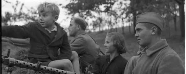 Propagandna fotografija prikazuje vojaka JNA na položajih skupaj 
z otroki iz bližnje vasi.