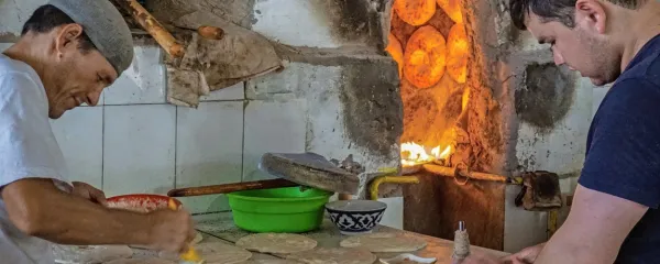 Uzbeka pripravljata nan (kruh) za peko na obodu glinene peči.