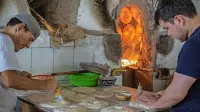 Uzbeka pripravljata nan (kruh) za peko na obodu glinene peči.