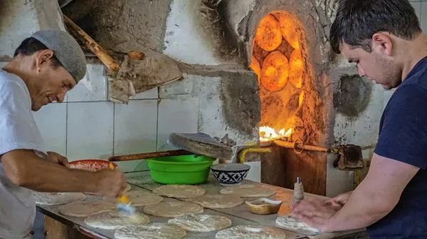 Uzbeka pripravljata nan (kruh) za peko na obodu glinene peči.