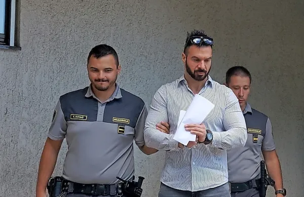 Gera  Mladenov (med pravosodnima policistoma)  je  na  sodišču  
hotel  pogledati  v  oči  Izolanu,  ki ga  je  pred  dobrim  letom  porinil  v  
svojega  porsche  cayenna in  odpeljal,    a  ga  je lahko  gledal le na  
ekranu.