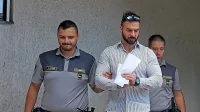 Gera  Mladenov (med pravosodnima policistoma)  je  na  sodišču  
hotel  pogledati  v  oči  Izolanu,  ki ga  je  pred  dobrim  letom  porinil  v  
svojega  porsche  cayenna in  odpeljal,    a  ga  je lahko  gledal le na  
ekranu.