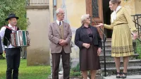 Družina Črv, pred rudarsko hišo Giser, pozdravlja povabljene na 
srebrno poroko rudarskega nadzornika Petra in žene Marjance.