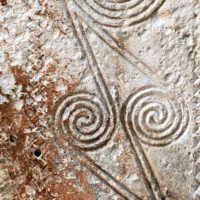 Detajl spiralno okrašene kamnite stele iz 
grobišča v Nazakciju na razstavi v Trstu