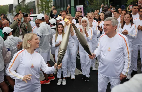 Predsednica komisije športnikov Mednarodnega olimpijskega 
komiteja (MOK) Emma Terho in predsednik MOK Thomas Bach s 
štafetama olimpijskega ognja.