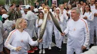 Predsednica komisije športnikov Mednarodnega olimpijskega 
komiteja (MOK) Emma Terho in predsednik MOK Thomas Bach s 
štafetama olimpijskega ognja.