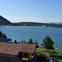 Klopinjsko jezero v svojem sončnem dnevu - turizem cveti, tam 
nekje na vodi pa je drobcena pika, ki plava na drugo stran.