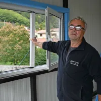 Predsednik gasilskega društva Mirjan Grdina kaže vlomljeno okno 
garaže, v kateri sta bila oba kombija.
