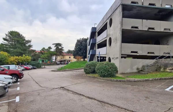 Lokacija ob grmovju pri parkirni hiši v Prisojah, kjer je krajanka 
kljub dovolilnici za parkiranje prejela globo.