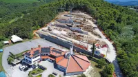 Podporni zid za župnijsko cerkvijo je sedaj v smeri proti gozdu 
daljši za 12 metrov - tega podaljška gradbeno dovoljenje ne 
omenja, zato pa projekt za izvedbo. Ali bi teh nekaj podaljšanih 
metrov gradbeno dovoljenje moralo omenjati ali ne, si sodelujoči 
niso enotni. 