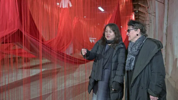 Elisabeth Scweeger, umetniška direktorica Evropske prestolnice 
kulture 2024 v Avstriji in japonska umetnica Chiharu Shiota (z 
desne) pred visečimi rdečimi vrvmi, delom odmevne instalacije v 
predorih nekdanjega koncewntracijskega taborišča Ebensee. 