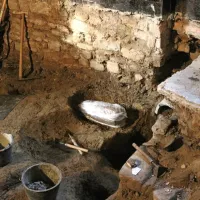 Pogled na poznoantični grob pod Collegiom dei Nobili. Amfora s 
posmrtnimi ostanki novorojenčka je ovita v folijo in pripravljena 
na dvig ter prenos v laboratorij, kjer se izvedejo poterenske 
analize.