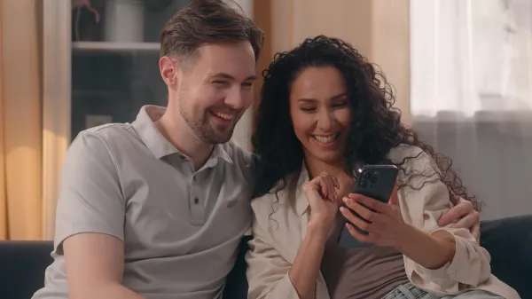 Multiracial happy couple family Caucasian man guy male Hispanic woman girl female talking using mobile phone together shopping online at home choose furniture goods purchase planning combined budget,Image: 962774048, License: Royalty-free, Restrictions:, Model Release: yes