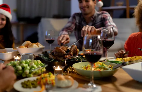 Front view of a young mixed race man wearing a Santa hat sitting at table at home with friends for Christmas dinner, carving the turkey,Image: 532715707, License: Rights-managed, Restrictions:, Model Release: yes, Credit line: Wavebreak Media LTD/Wavebreak/Profimedia