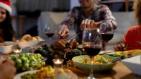 Front view of a young mixed race man wearing a Santa hat sitting at table at home with friends for Christmas dinner, carving the turkey,Image: 532715707, License: Rights-managed, Restrictions:, Model Release: yes, Credit line: Wavebreak Media LTD/Wavebreak/Profimedia
