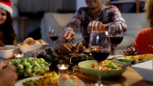 Front view of a young mixed race man wearing a Santa hat sitting at table at home with friends for Christmas dinner, carving the turkey,Image: 532715707, License: Rights-managed, Restrictions:, Model Release: yes, Credit line: Wavebreak Media LTD/Wavebreak/Profimedia