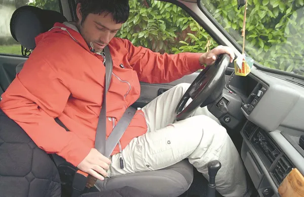 voznik med zapenjanjem varnostnega pasuvarnostni pas v avtomobilu